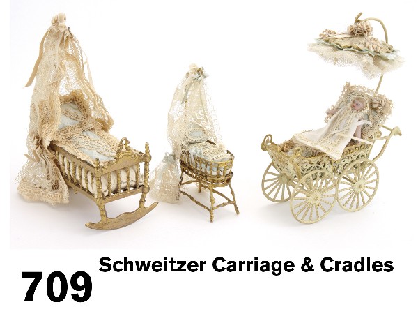 Schweitzer Carriage & Cradles: painted and gilded soft metal carriage with parasol and small bisque doll (repair to 1 leg), rocking cradle with netted canopy and carrying cradle with gilded bamboo base. Size: carriage 3.5" l. x 5" 