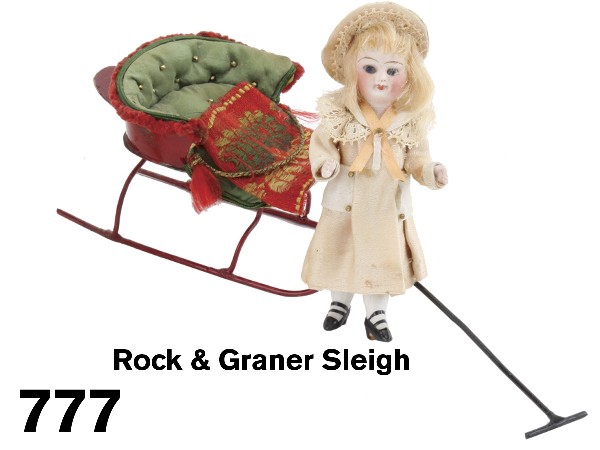 Rock & Graner Sleigh: painted tin upholstered sleigh with gold beaded tufted seat with woven sleigh blanket, attributed to Rock & Graner; offered with small jointed bisque dolls' house doll with blue eyes, blonde wig and s