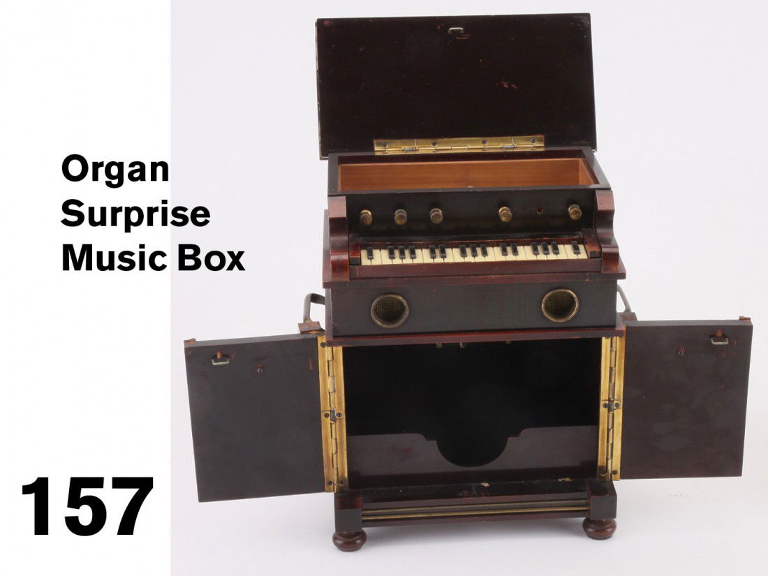 Organ Surprise Music Box: intricately crafted piano form in rosewood toned wood, the box has opening top lid and two opening lower doors with latch release hidden on back, access to winding the Swiss music movement is gained t