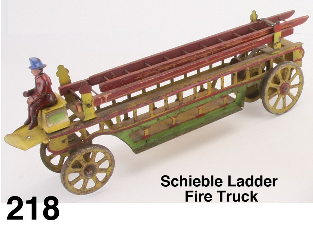 Schieble Ladder Fire Truck: painted pressed steel inertia powered crank ladder truck with bell and painted cast iron fireman Size: 19.5" l.