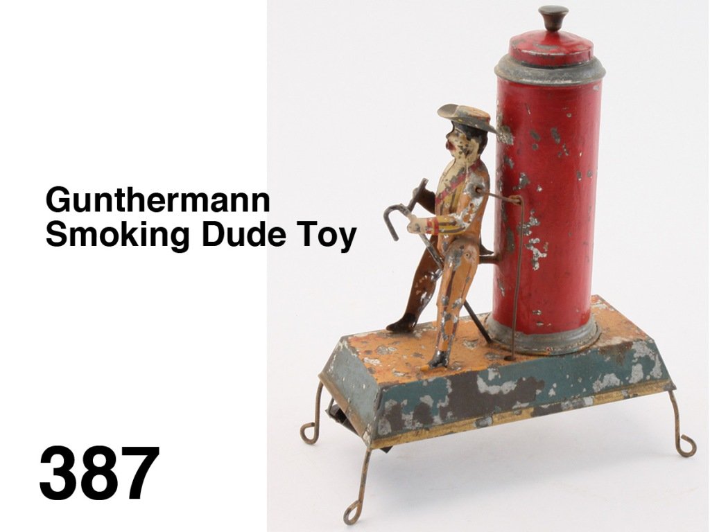 Gunthermann Smoking Dude Toy: painted tin with ingenious clockwork mechanism: to operate smoke is blown into the canister and the lid closed then a paper bellows beneath the canister pushes smoke through a tube thence out of the m