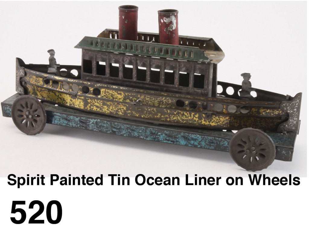 Spirit Painted Tin Ocean Liner on Wheels: a finely crafted nautical floor toy of pierced and embossed tin with two figures on deck, open worked tin wheels, embossed waves on blue stained base, European manufacture - probably French Size: 12.5