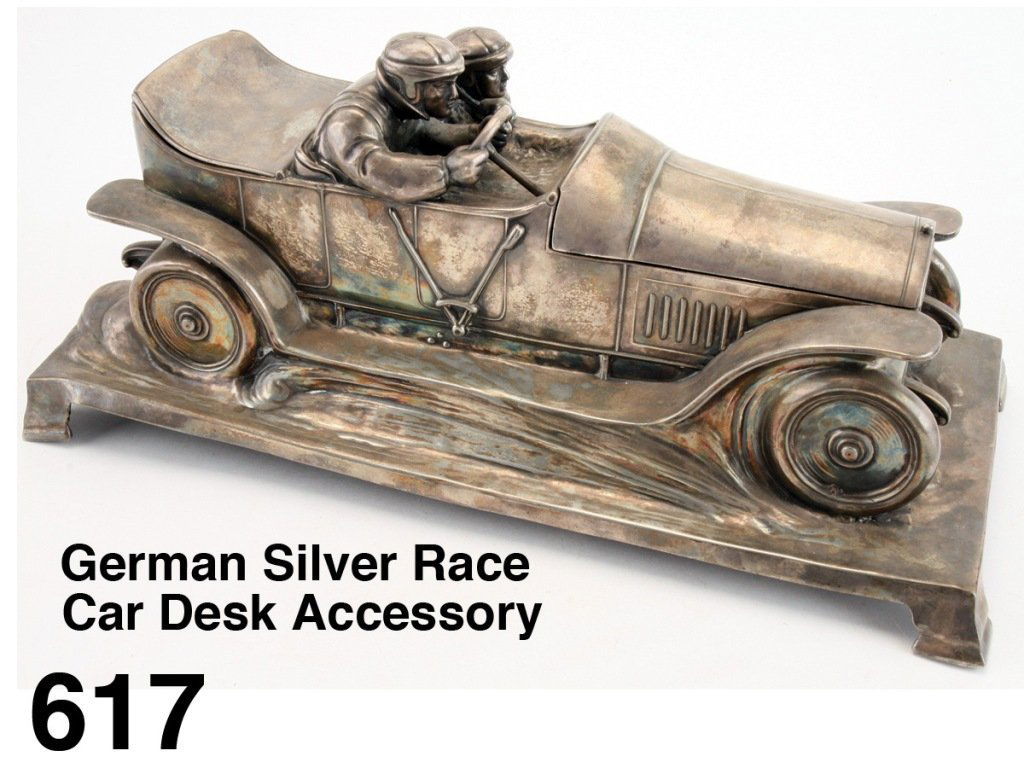 German Silver Race Car Desk Accessory: A SILVER-PLATED DOUBLE INKWELL BY WURTTEMBERGISCHE METALLWAREN FABRIK Molded as two race car drivers in a vintage car, the hood and trunk open to reveal two compartments. Very nicely detailed with ste