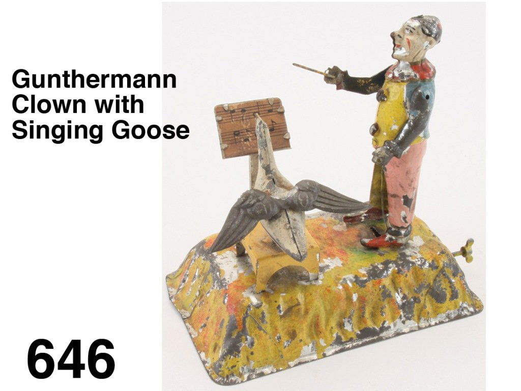 Gunthermann Clown with Singing Goose: painted tin clockwork, clown waves baton, goose bobs up and down in front of music stand - bellows provide chirping sound Size: 6.75" w., 7" t.