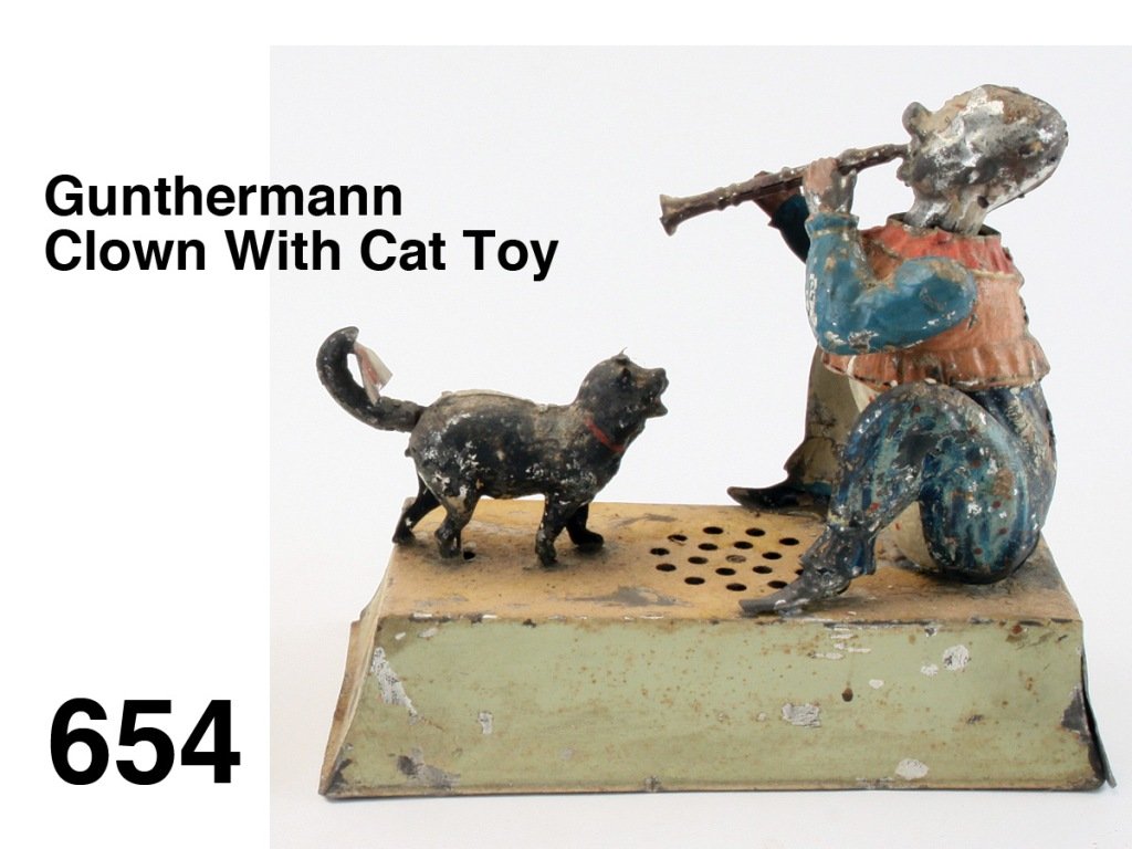 Gunthermann Clown With Cat Toy: painted tin clockwork with plink plunk music, cute action: clown bobs head and horn up and down while cat wags tail which is holding music Size: 8.5" l., 8" t.