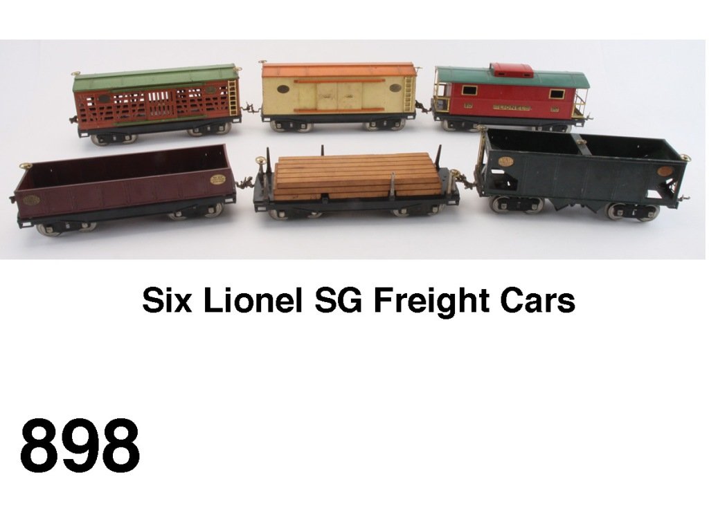 Six Lionel SG Freight Cars: standard gauge painted tin - 211 flat car with lumber (missing 2 stakes), 212 gondola, 213 livestock car, 214 box car, 216 ballast car and 217 caboose Size: appr. 13" l. ea.