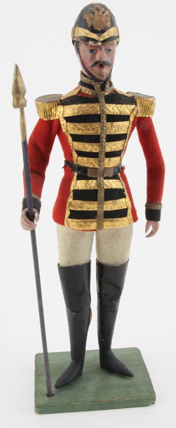 Pfeiffer Soldier on Guard Duty: cloth dressed figure with earlier style painted paper mache head and hands, dressed in red and black jacket with gold Dresden paper trim, gold painted epaulets, thigh high black boots, and high black