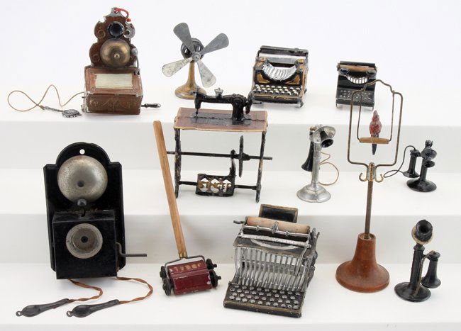 Metal & Tin Dolls' House Phones, Fans, etc.: painted soft metal and tin grouping includes parrot on stand (marked Germany), 3 typewriters, Singer sewing machine, Ideal carpet sweeper, 4 blade fan, and 5 early telephones bird stand 5" t.