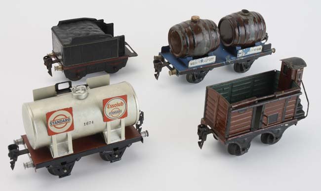 Four Marklin 0 Gauge Train Cars: includes 'Standard - Essolub' tank car in excellent condition, a twin barrel tank car 'Wein-Transport - Rodesheim No 416' - (very good with some paint loss and missing caps), goods wagon with guard to