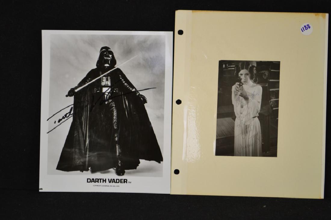 Star Wars Star Autographs: Two Star Wars photographs, one featuring Carrie Fisher as Princess Leia wearing a white dress bearing a firearm, measuring 5.75" x 3.75" signed by actress, and Darth Vader (signed as Darth Vader) on a