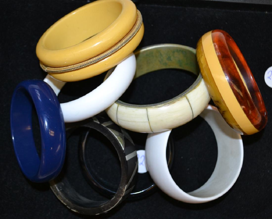 Bangle Bracelets: Including a tri-colored Bakelite bangle, a cream Bakelite bracelet with a brass band, a silver inlaid bangle and more.