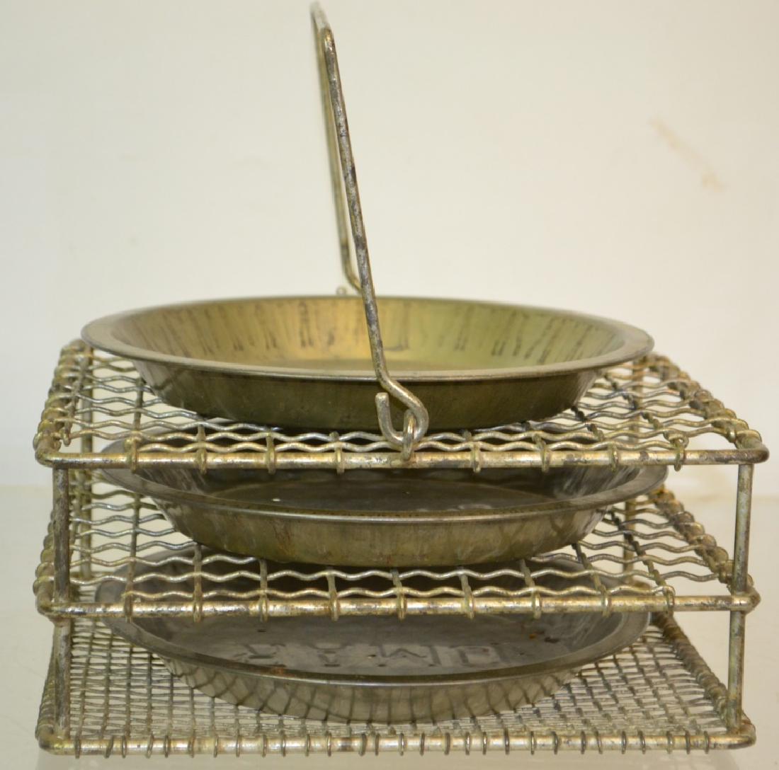 General Store Pie Stand: Item measures approx. 4"h x 9"w x 9"d. It is constructed of wire, has the original handle and comes with 3 OMAR tin pie plates. .
