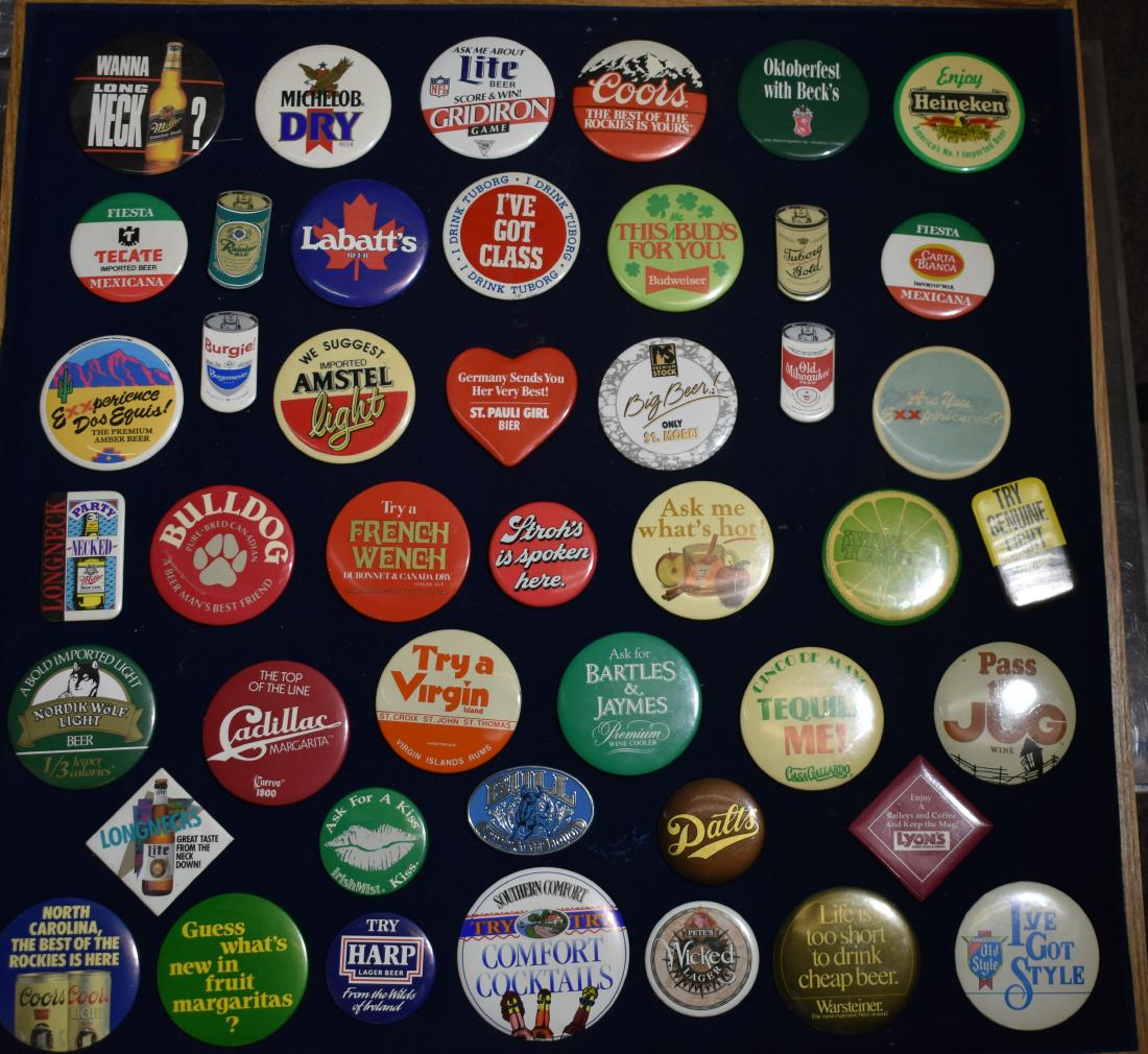 Collection of Beer and Cocktail Pin Backs: Over 35 pin backs including Coors, Beck's, Heineken, Budweiser, and various others. Items are displayed in an oak showcase measuring 24"h x 24"w x 2"d.