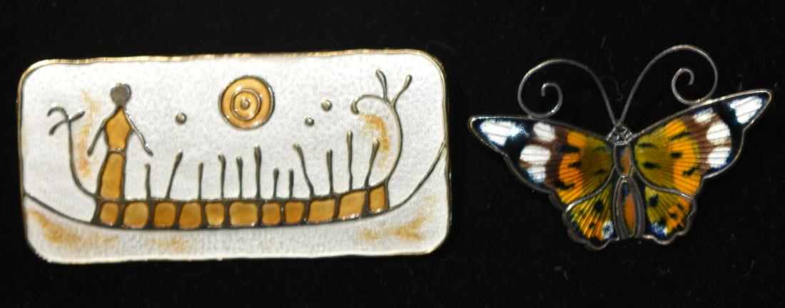 "David Andersen" Sterling Pins: The larger measures approx. 2 1/2" in length and is an enameled pin depicting a man in a boat. It is titled "Rock Carving from Norway 1000-500 BC". The other pin is a sterling enameled Monarch butterf