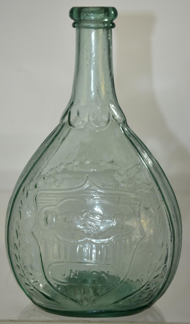 Early Hand Blown Union Bottle: Item measures approx. 9"h. It has clasped hands and the word "Union" in a shield on one side and an eagle with a banner on the other side. Bottle has a polished pontil bottom.