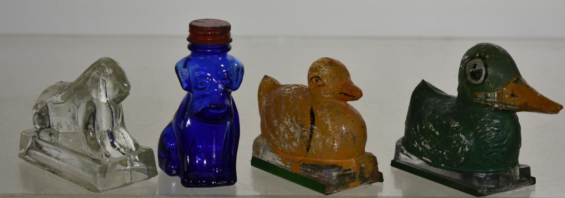 Four Vintage Glass Animal Candy Containers: Including the "Ugly Duckling" with original paint and tin bottom, a duck on a plain top basket with the original paint and tin bottom, a crouching rabbit and a cobalt puppy with the original cap.