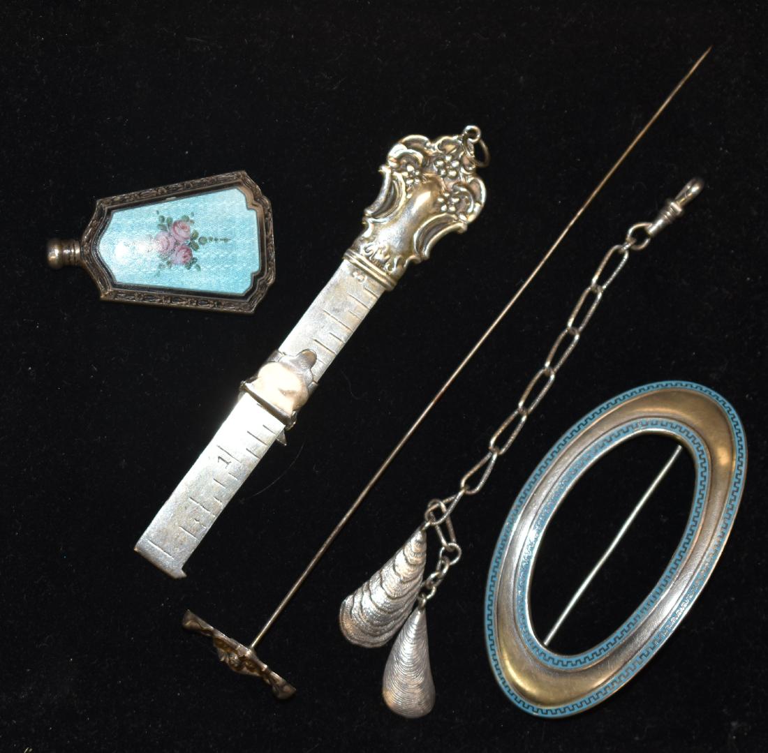 Victorian Sterling Jewelry: Including a "Schreibler" sterling watch fob with two oyster shells, a sterling buckle pin marked "Kerr", an enameled perfume bottle, a "Chatelaine" tape measure and a floral sterling hat pin.