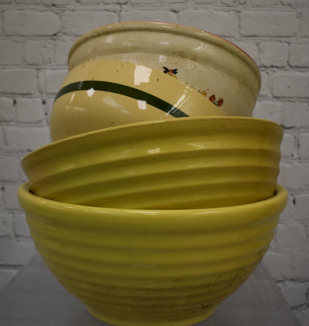 Grouping of Vintage Mixing Bowls: Including two large yellow ware mixing bowls - one has a hairline and the other has crazing, a white Ironstone bowl, a Watt ware apple bowl with a rim chip and others. Items show wear consistent with 