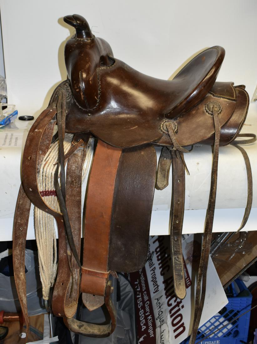 "El Paso" Western Saddle: Saddle has four escutcheons with tassels, wooden stirrups, belly straps and "The El Paso Saddle Company" stamp. The wool protector shows loss consistent with age and usage.
