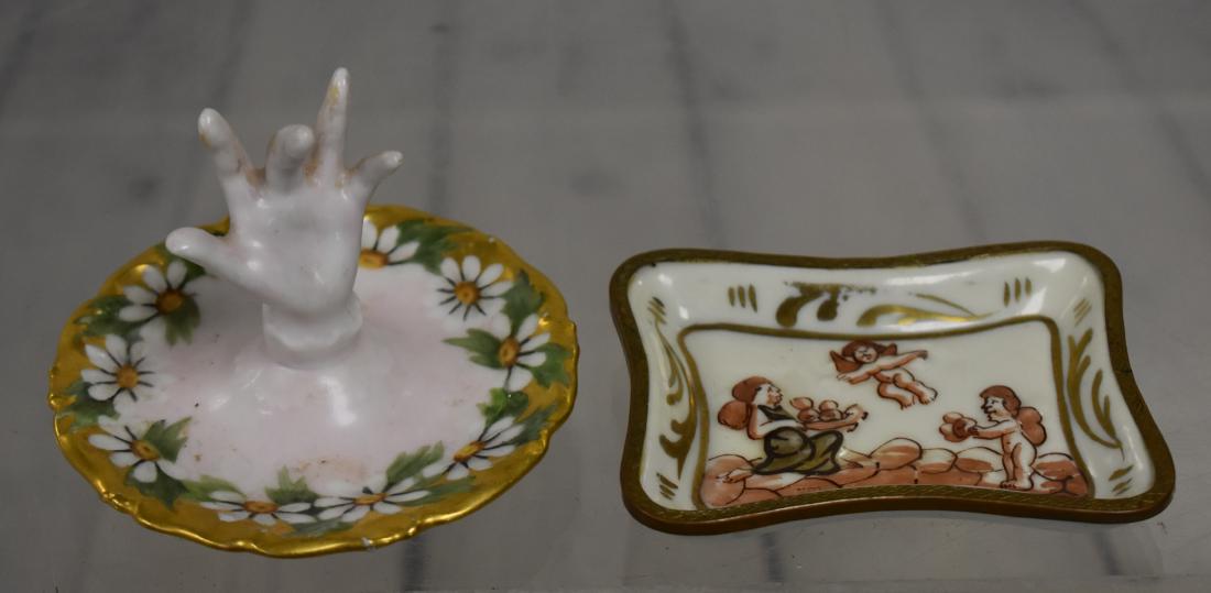 Two French Ring Dishes: First measures approx 3"dia. It has hand paint flowers and gold flashing with a raised hand for a ring. Item is marked T&V Limoges. The second is a ring tray with cherub decoration and is marked "Hand