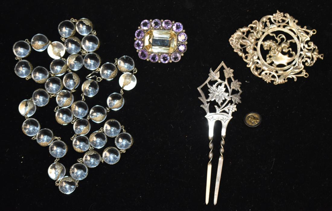 Victorian Sterling Jewelry Grouping: Including a rock crystal necklace with silver daisy accents, a large sterling brooch with a lion in the center and a dolphin at the top, a floral sterling hair comb, a pin with purple exterior and lar