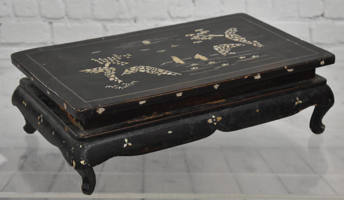 19th Century Miniature Chinese Bench: Item measures approx. 5"h x 15"w x 9"d. It is varnish teakwood with mother of pearl inlay. It is a footed bench and shows some loss at base of frame consistent with age and usage.