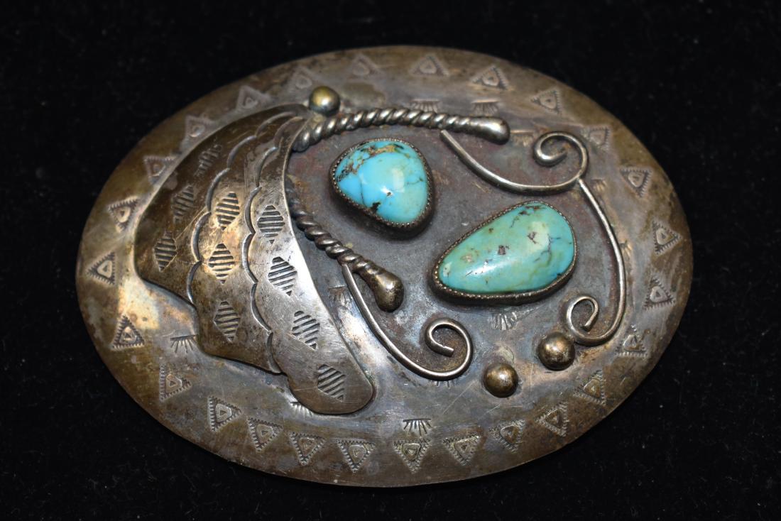 Native American Signed Silver Belt Buckle: The buckle has leaf decoration with two pieces of turquoise and Navajo decoration surrounding the piece. Signed TG.