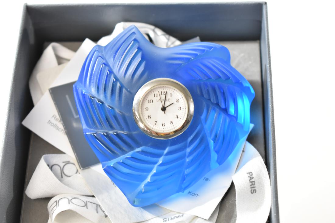 Blue Lalique St. Valentine Clock: Measures approx. 3" across. It is frosted blue Lalique crystal and etched "Lalique France" on back. Comes in original box with paperwork.