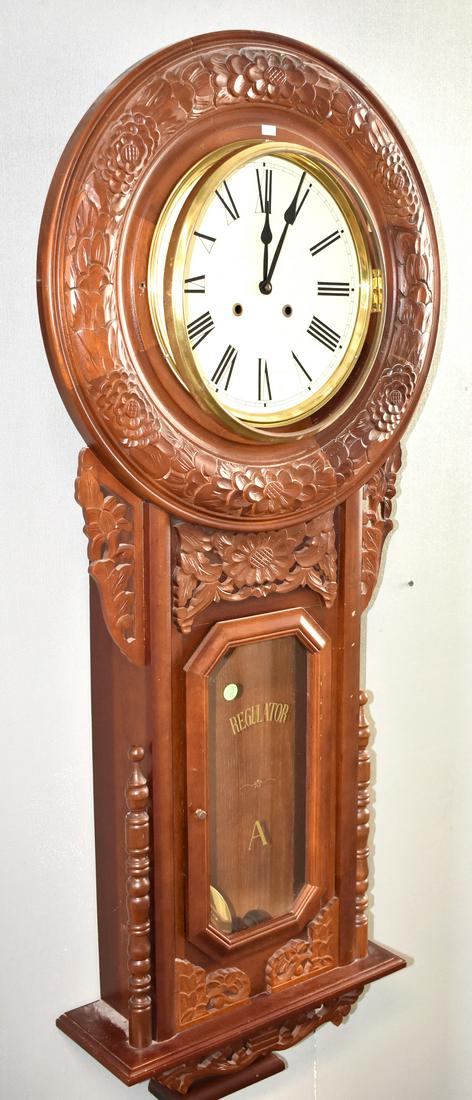 Ornate Regulator Wall Clock: Clock measures approx. 56"h. It has a floral carved mahogany body, original key and pendulum, glass marked "Regulator A" and base finial has a dented tip. Note: bezel and catch are missing.