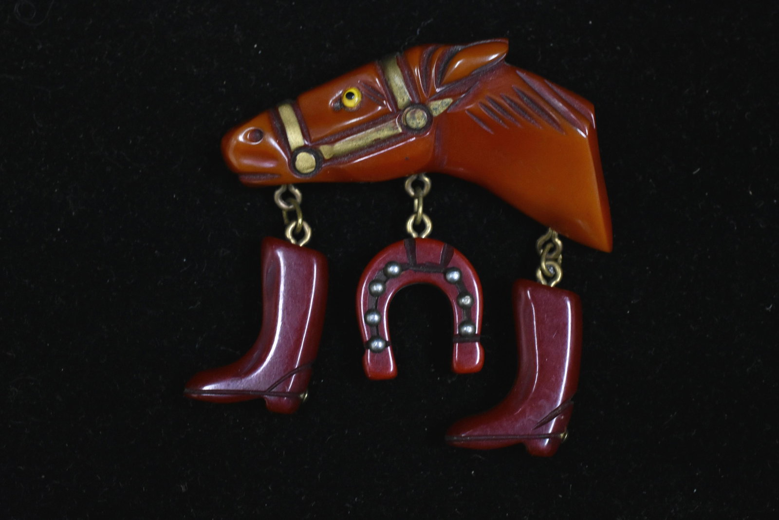 Vintage Red Bakelite Horse Charm Pin: The pin has a horsehead with boot and horseshoe charms.