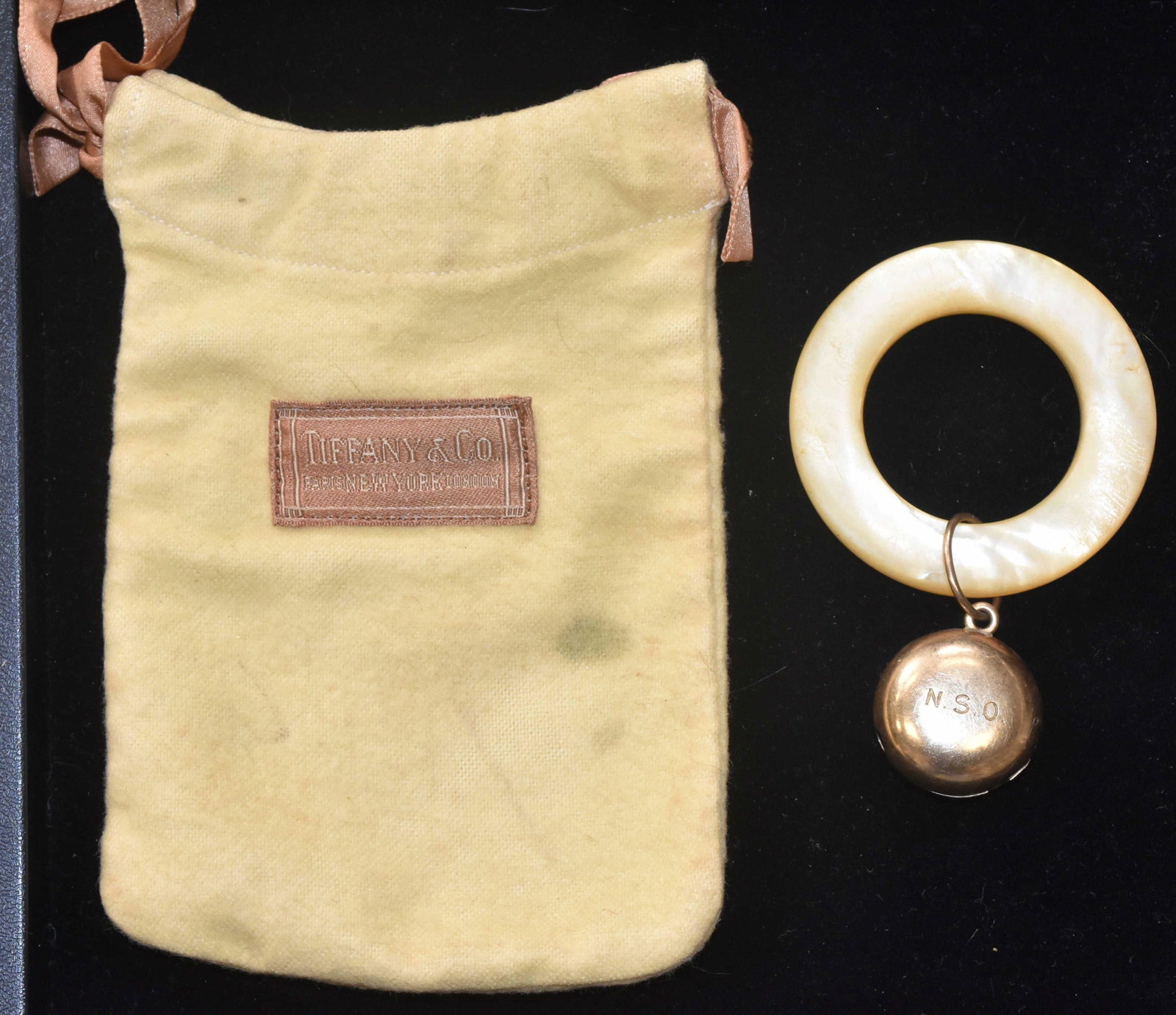 Tiffany & Co. Teething Ring w/ 14K Gold Rattle: Ring measures approx. 2 1/4"dia and is mother of pearl. Rattle is marked "Tiffany & Co, 14K" and is monogrammed "N.S,O" Item comes with the original pouch marked "Tiffany & Co." Appears to date from t