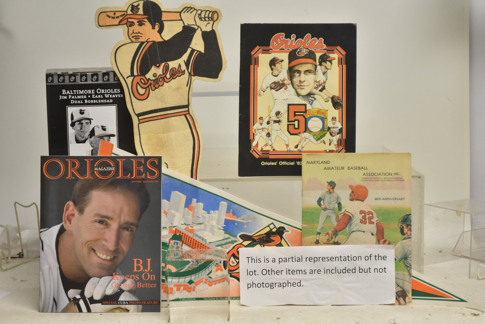 Orioles and other Baseball Related Items: Including a an autographed Mike Cuellar baseball, a Cal Ripken candy bar box, a Jim Palmer bobble head, two large vinyl Orioles banners, an Orioles figural pennant and another, 1970's and 1980's yearb