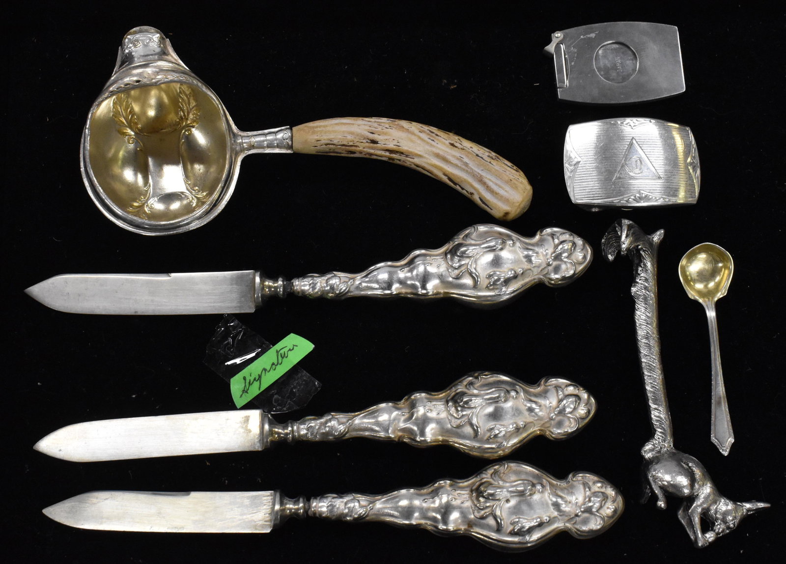 Art Nouveau "Silveroin" and other Items: Three fruit knives, a sterling belt buckle, a silver plated rabbit knife rest, a ladle marked "Sheffield", a sterling salt spoon and a cigar cutter.
