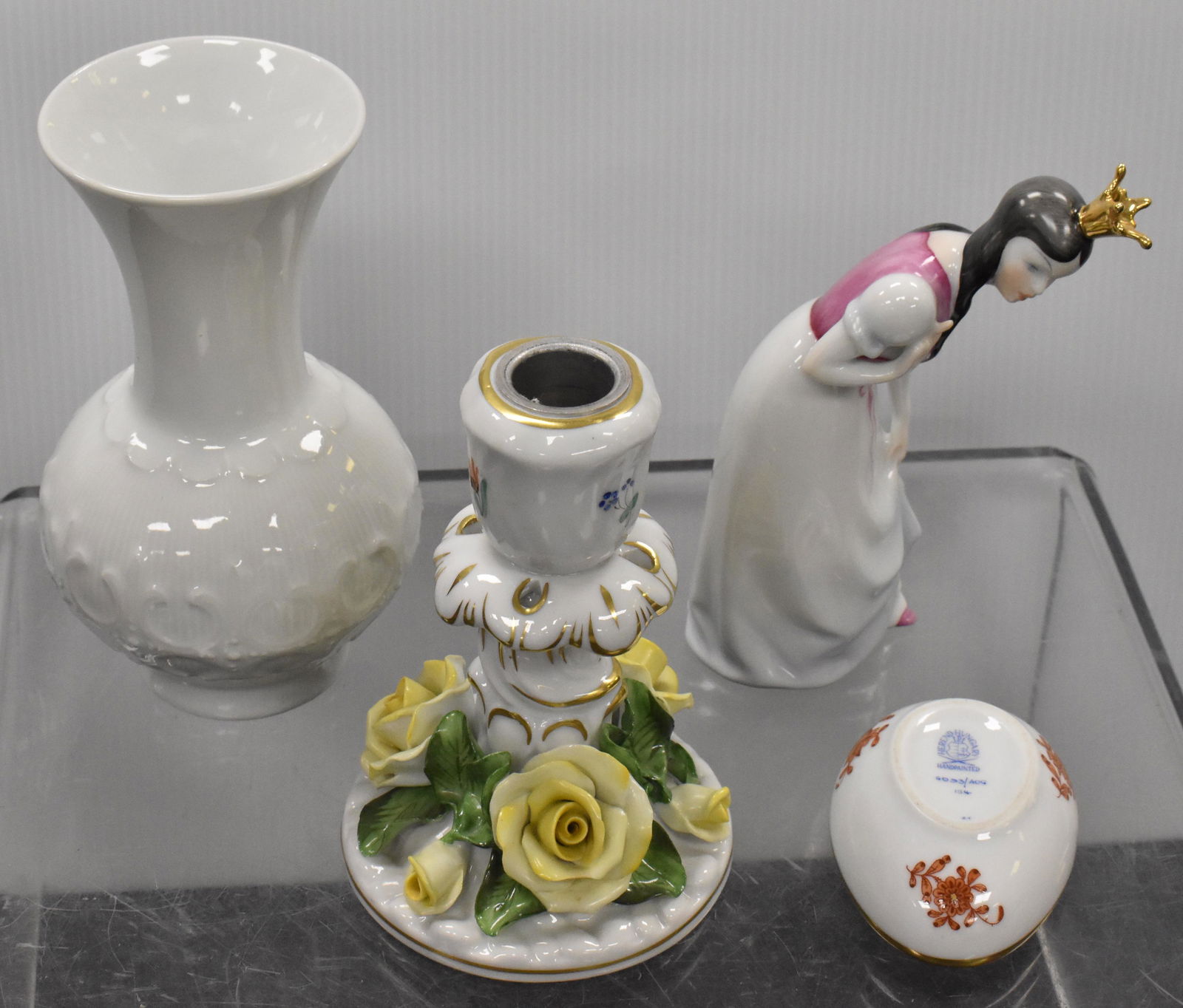 Herend and KPM Grouping: A Herend figure of a princess measuring approx. 6"h, a Herend floral candlestick, a white KPM bud vase and the base to a Herend egg.