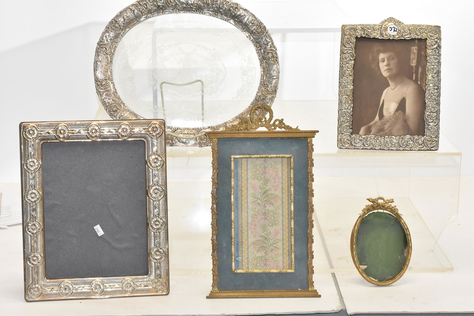 Silver Plate Picture Frames and a Tray: Larger frame measures approx. 12"h x 10"w. Both silver plated frames have a felt back with stand. Lot also includes a silver plated tray with glass insert and a windmill motif and two brass frames one