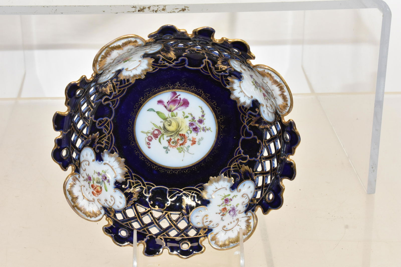 Reticulated Meissen Hand Painted Bowl: Bowl measures approx. 8 1/2"dia. It has a cobalt background with hand painted flowers, a reticulated body with good gold flashing and the Meissen crossed sword mark on bottom.