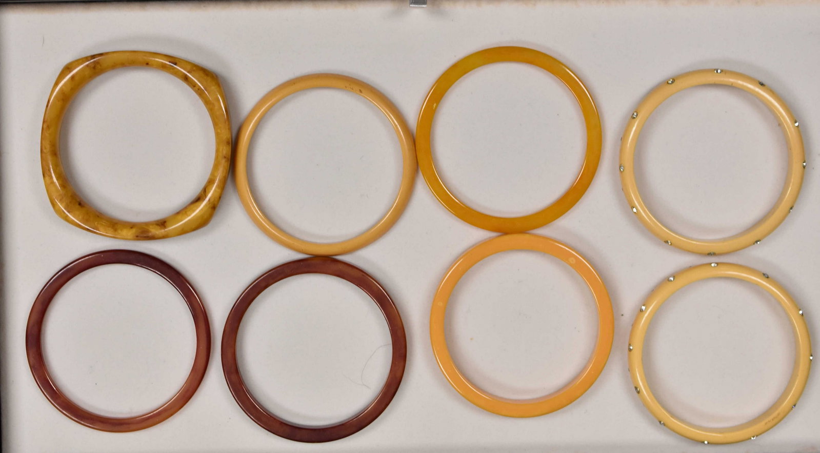 Vintage Bakelite Bangle Grouping: Bracelets include two with inset rhinestones, two red marbleized bangles and others in various hues. Total of eight bangles.