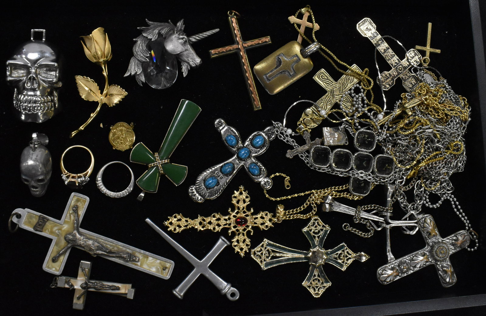 Religious and Figural Jewelry: A large selection of crosses, two skull pendants, a pewter unicorn with crystal, a rose pin marked "Giovanni" and various rings. Note: chains are tangled.
