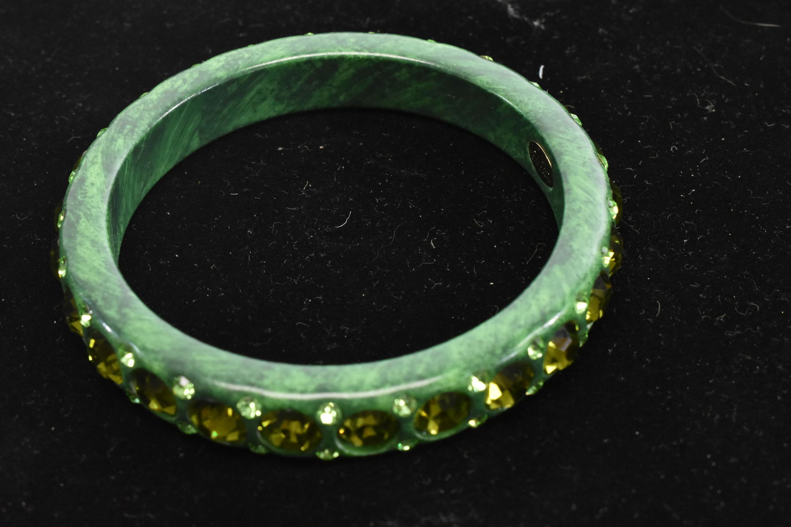 Vintage Bob Mackie Bangle Bracelet: Green bracelet encircled with large and small green stones. Item has a gold Bob Mackie tag on interior.