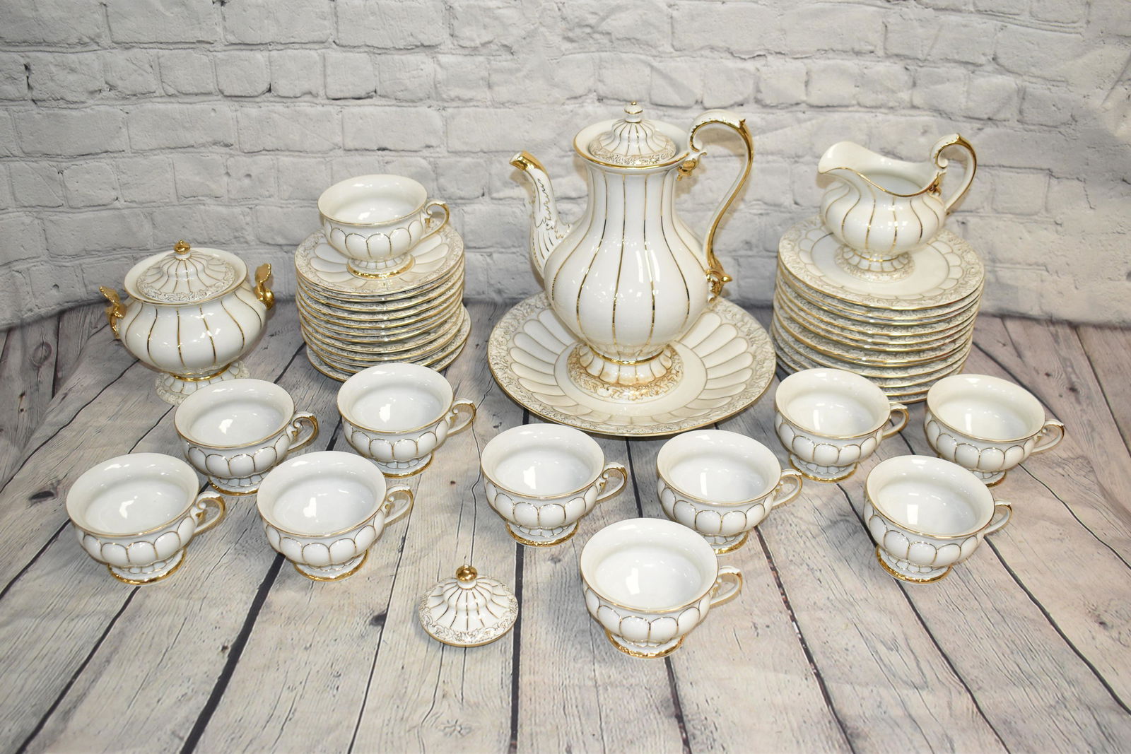 Large Gold Flashed Meissen Tea Set: Teapot measures approx. 11"h and has a matching sugar bowl with minor flakes to handle and a creamer.. Teapot has a small chip at base. Lot also an under plate, ten cups and saucers and twelve bread &