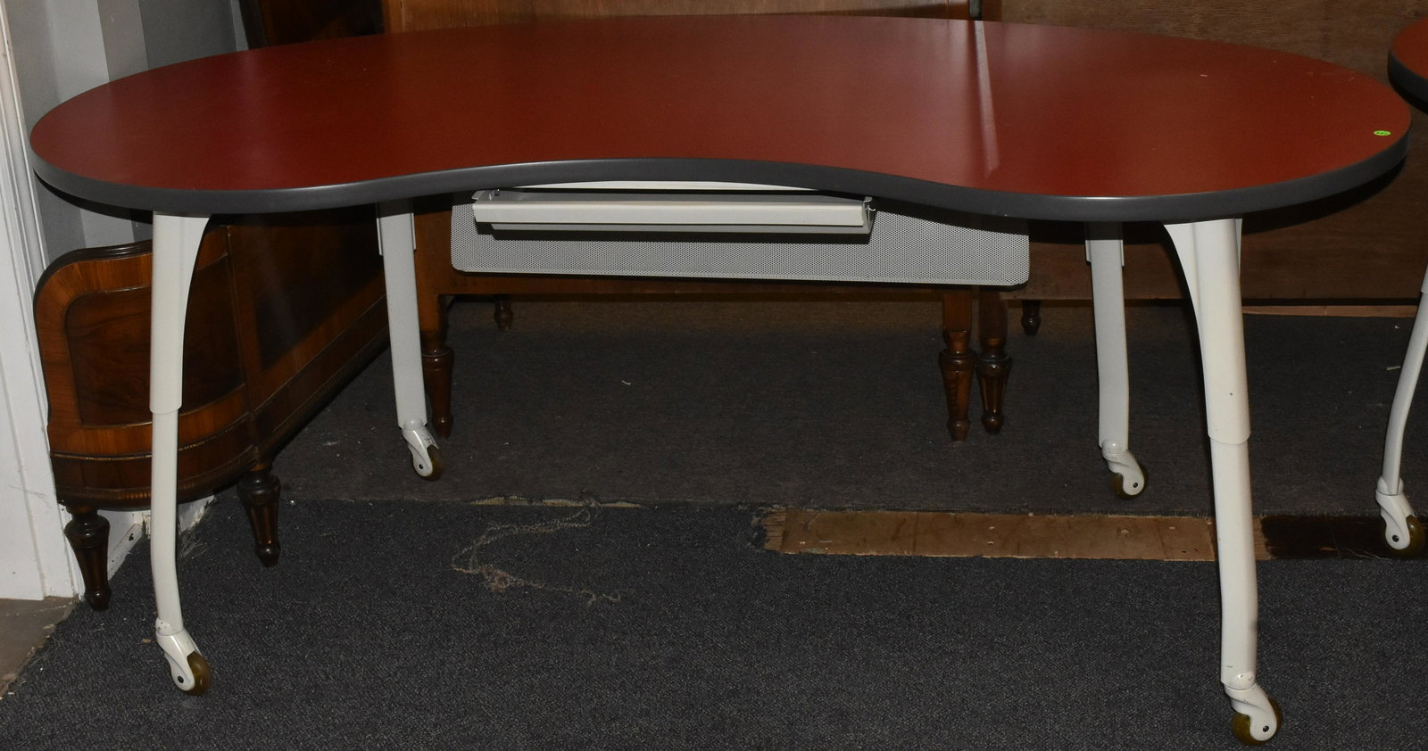 Allsteel Post Modern Kidney Desk: Measures approx. 30"h x 72"w x 30"d at center. Item has a red top, metal splay legs and bearing wheels. It has a pull out drawer and a protective screen flap Drawers open but key is lost.. item is del