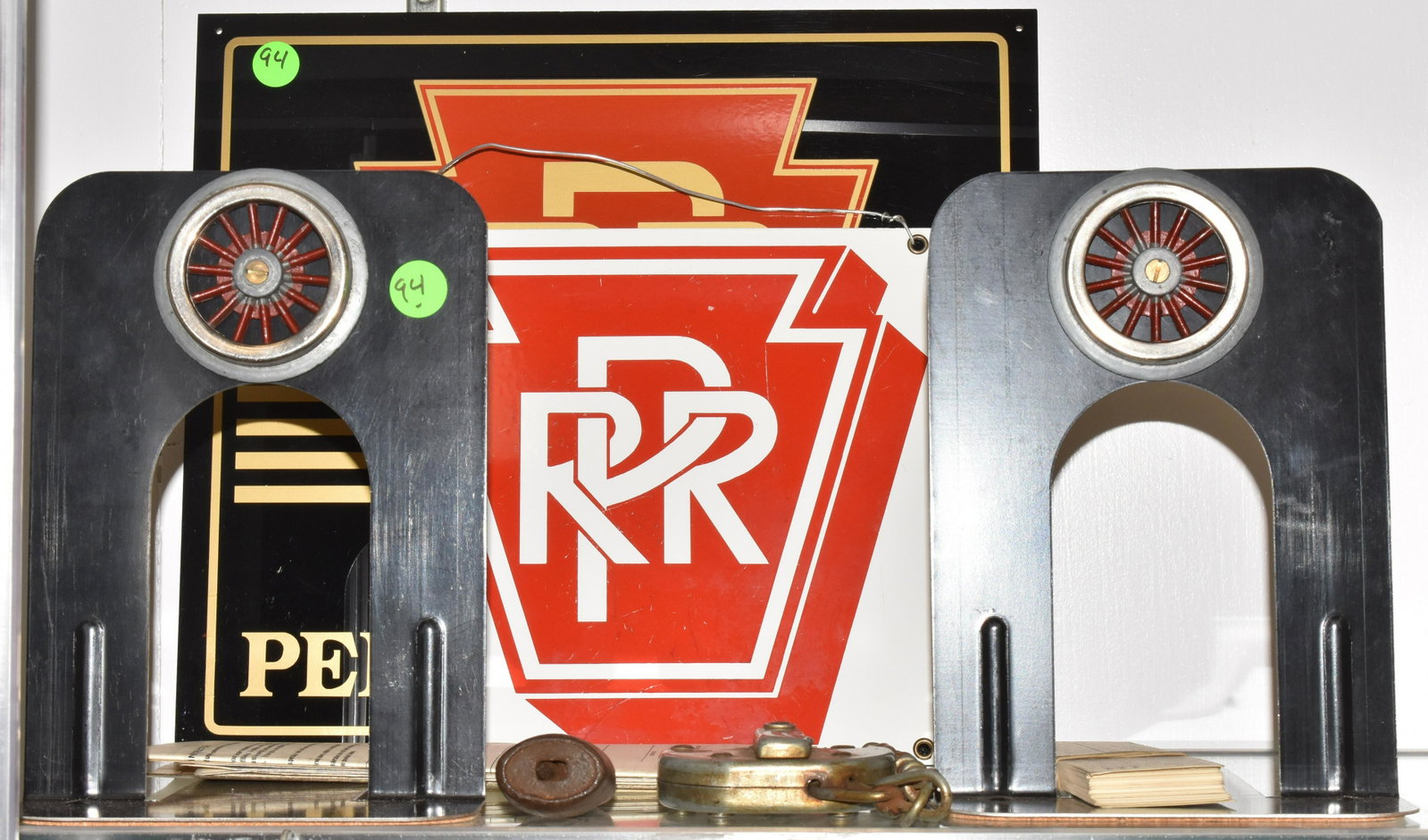 PRR Sign and Railroad Items: Lot includes a contemporary enameled PRR sign measuring approx. 8 1/2"h x 8 1/2"w, a Lucite PRR sign with a cardboard back, two railroad locks without keys, a pair of railroad bookends and other railr