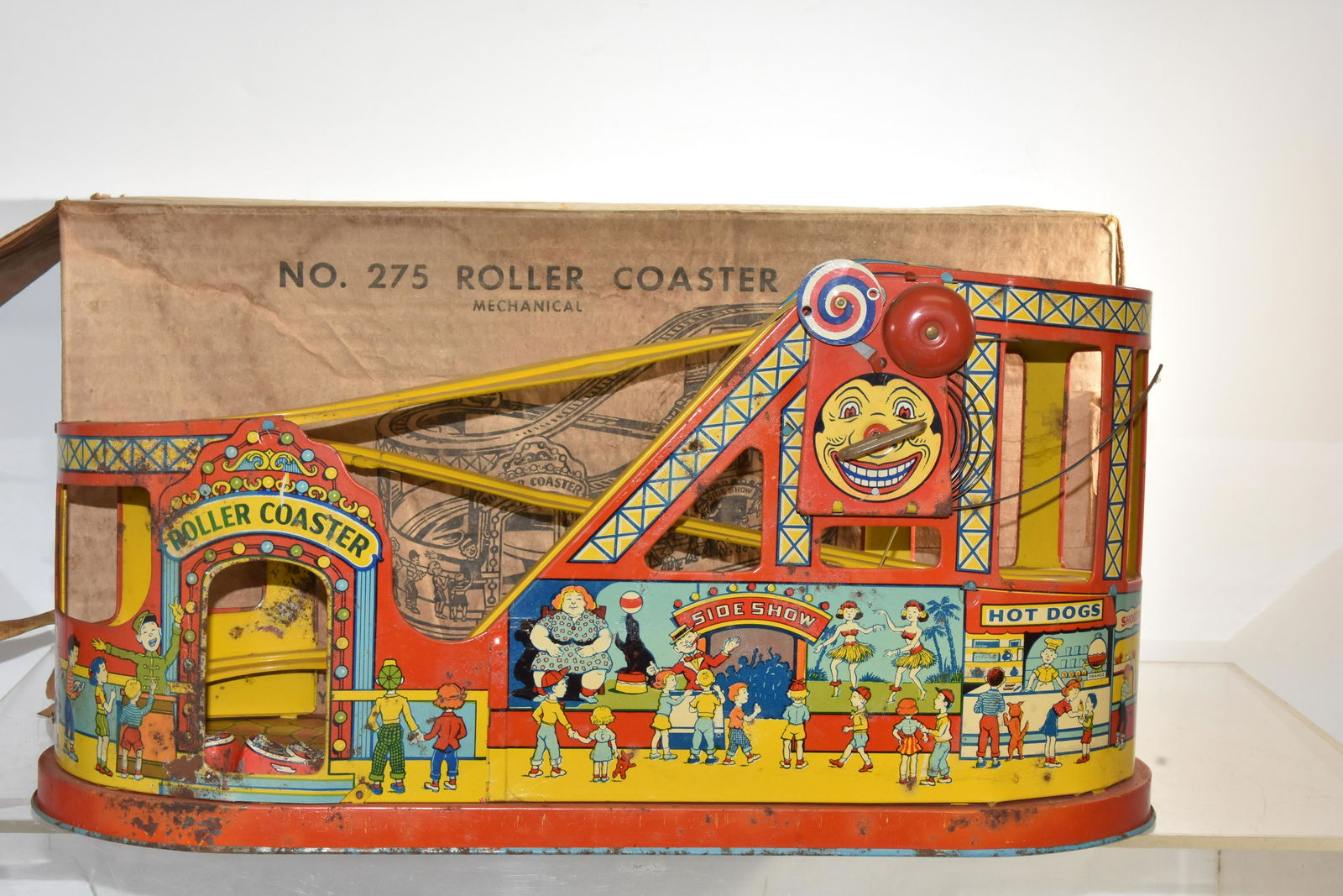 J. Chein Tin Roller Coaster in Box: Measures approx. 10"h x 19" in length. It has good graphics with some oxidation. Retains two roller coaster cars and belt drive. It is a model #275 roller coaster with original box. Note: Key spring h