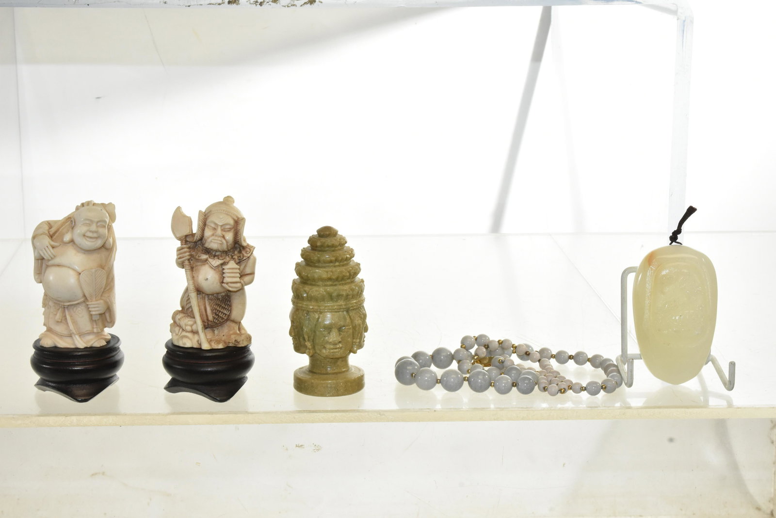 Asian Figures and a Blind Pull: Including a white mineral blind pull with a bird motif, a stone totem, a beaded gray mineral necklace and two figures that may be resin.