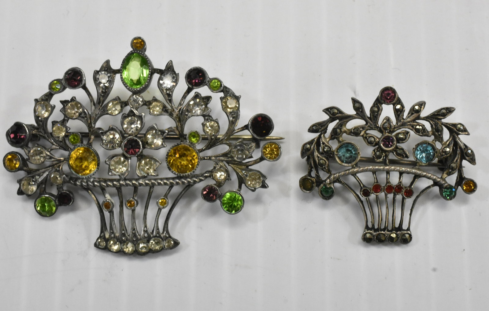 Georgian Sterling Basket Pins: Both pins are in the shape of a flower basket and have multi colored stones. Both are marked "Germany".