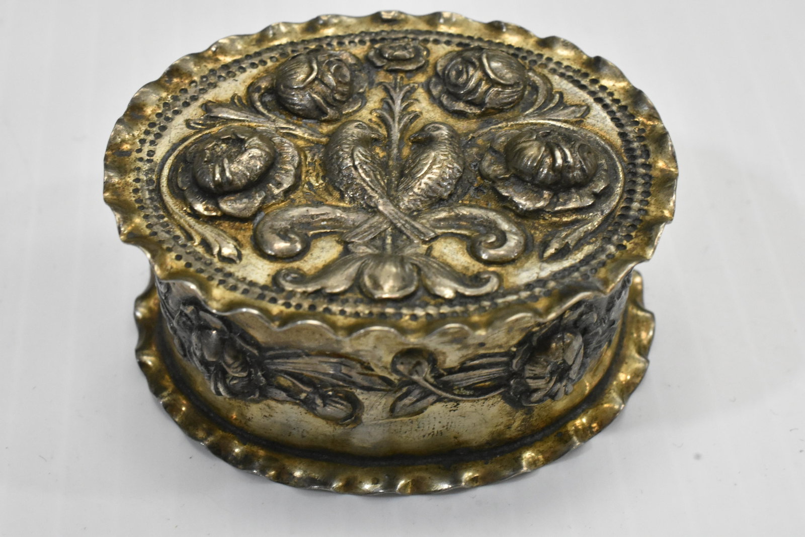 18th Century Sterling Repousse Box: Measures approx. 2 1/4" in length. It has a pair of doves and flowers on lid. Lid and base have crimped edges. Item has a floral body and hallmarks of a crowned leopard, a standing lion and a dolphin