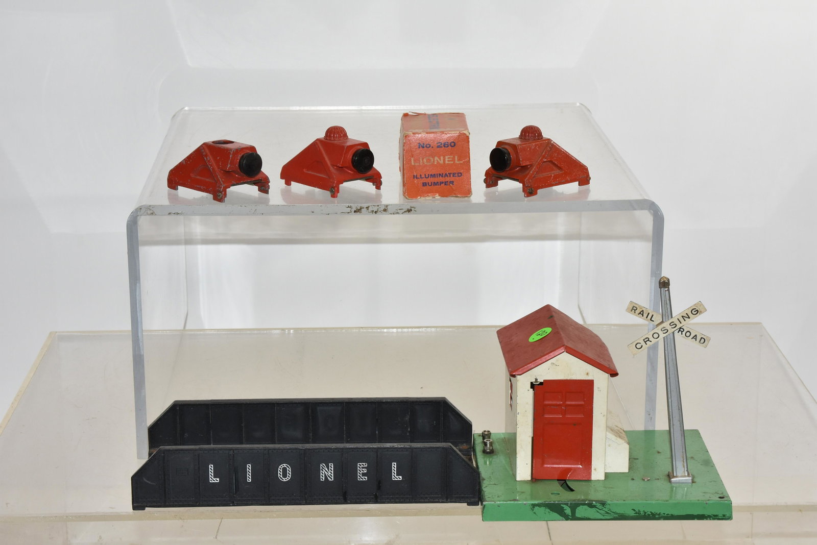 Vintage Lionel Crossing Guard Shed and more: Lot includes item #45N crossing guard shed with man (missing lantern), three Lionel #260 illuminated bumpers (one with box and one missing bulb cover) and a Lionel bridge section with a metal base.