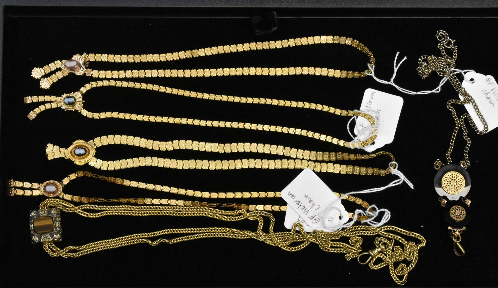 Victorian Style Gold Fill Jewelry: Including four Victorian style gold fill necklaces with cameos, a necklace with a tiger eye pendant and fob and a vintage fob necklace with damage to black stones. Weights on tags are approx.