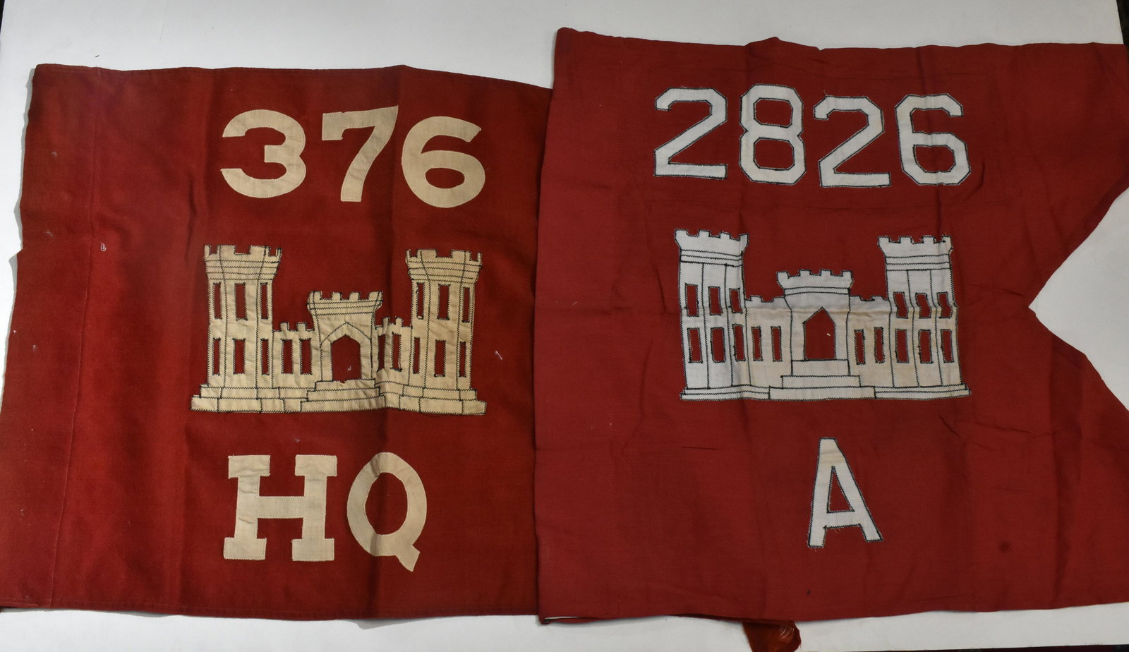 Pair of Army Corps of Engineers Castle Banners/Flags: Each measures approx. 18"h x 27" in length. They are applique on red cloth and one shows wear near tips of flag. That’s what the castle represents and the numbers are the unit numbers.