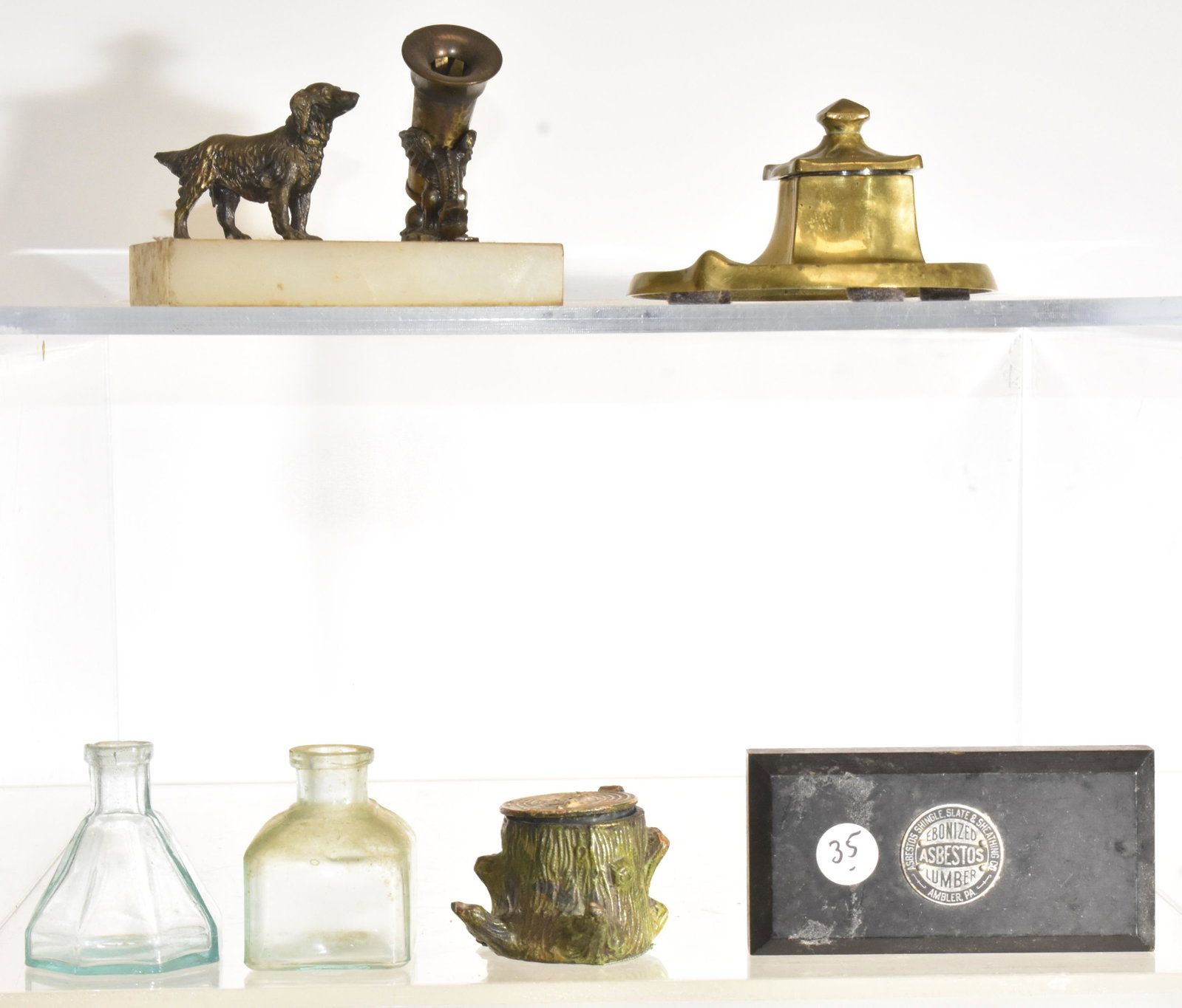 Vintage Ink Wells and more: A brass Art Nouveau ink well, an ink well in the form of a tree stump, a pen holder paper weight with a dog and a dragon, two glass ink bottles and an advertising paper weight.